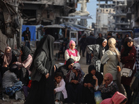 Displaced and local Palestinian residents of Khan Yunis wait outside a bakery for fresh bread in the southern Gaza Strip city on November 19...