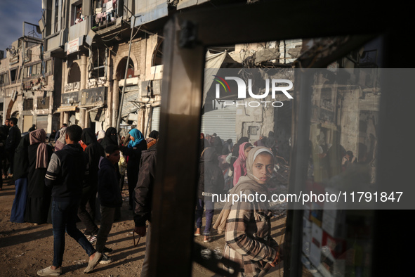 Displaced and local Palestinian residents of Khan Yunis wait outside a bakery for fresh bread in the southern Gaza Strip city on November 19...