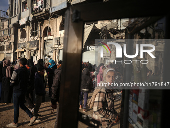 Displaced and local Palestinian residents of Khan Yunis wait outside a bakery for fresh bread in the southern Gaza Strip city on November 19...