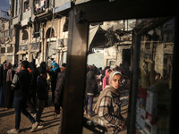 Displaced and local Palestinian residents of Khan Yunis wait outside a bakery for fresh bread in the southern Gaza Strip city on November 19...