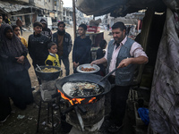 Palestinians wait for their falafel orders at a makeshift takeaway spot in Khan Yunis, Gaza Strip, on November 19, 2024, amid the ongoing wa...