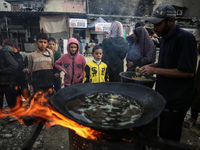 Palestinians wait for their falafel orders at a makeshift takeaway spot in Khan Yunis, Gaza Strip, on November 19, 2024, amid the ongoing wa...