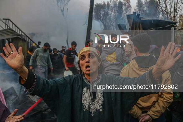 A woman reacts as firefighters and civilians work to extinguish a fire on residential houses in Srinagar, Jammu and Kashmir, on November 19,...