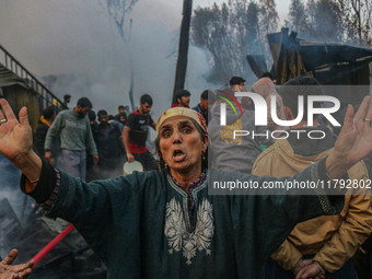 A woman reacts as firefighters and civilians work to extinguish a fire on residential houses in Srinagar, Jammu and Kashmir, on November 19,...