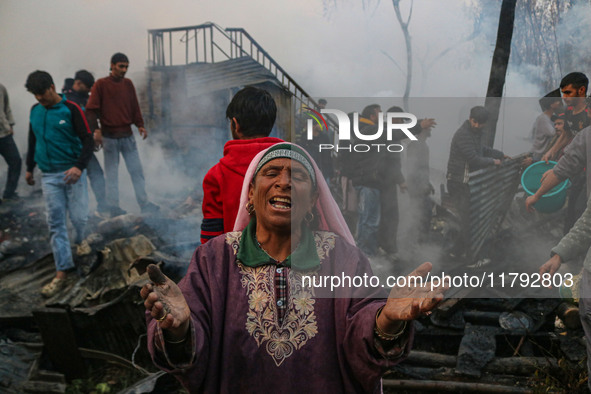 A woman reacts as firefighters and civilians work to extinguish a fire on residential houses in Srinagar, Jammu and Kashmir, on November 19,...