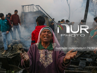 A woman reacts as firefighters and civilians work to extinguish a fire on residential houses in Srinagar, Jammu and Kashmir, on November 19,...