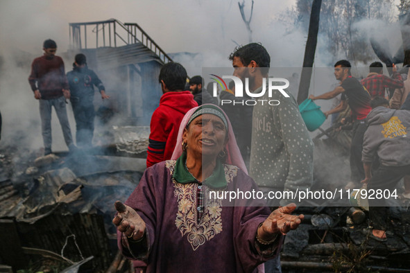 A woman reacts as firefighters and civilians work to extinguish a fire on residential houses in Srinagar, Jammu and Kashmir, on November 19,...