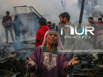 A woman reacts as firefighters and civilians work to extinguish a fire on residential houses in Srinagar, Jammu and Kashmir, on November 19,...