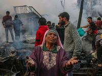 A woman reacts as firefighters and civilians work to extinguish a fire on residential houses in Srinagar, Jammu and Kashmir, on November 19,...