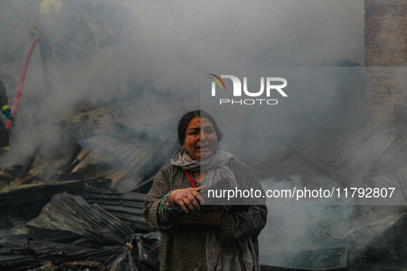 A woman carries her belongings as firefighters work to extinguish a fire on residential houses in Srinagar, Jammu and Kashmir, on November 1...