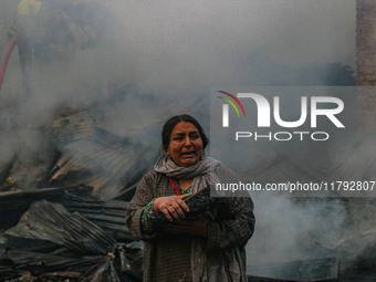 A woman carries her belongings as firefighters work to extinguish a fire on residential houses in Srinagar, Jammu and Kashmir, on November 1...