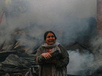 A woman carries her belongings as firefighters work to extinguish a fire on residential houses in Srinagar, Jammu and Kashmir, on November 1...