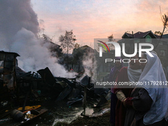 Women weep as firefighters and civilians work to extinguish a fire on residential houses in Srinagar, Jammu and Kashmir, on November 19, 202...