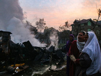 Women weep as firefighters and civilians work to extinguish a fire on residential houses in Srinagar, Jammu and Kashmir, on November 19, 202...