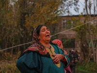 A woman weeps as firefighters and civilians work to extinguish a fire on residential houses in Srinagar, Jammu and Kashmir, on November 19,...