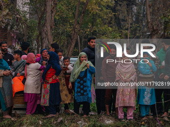 People watch from a distance as firefighters work to extinguish a fire on residential houses in Srinagar, Jammu and Kashmir, on November 19,...