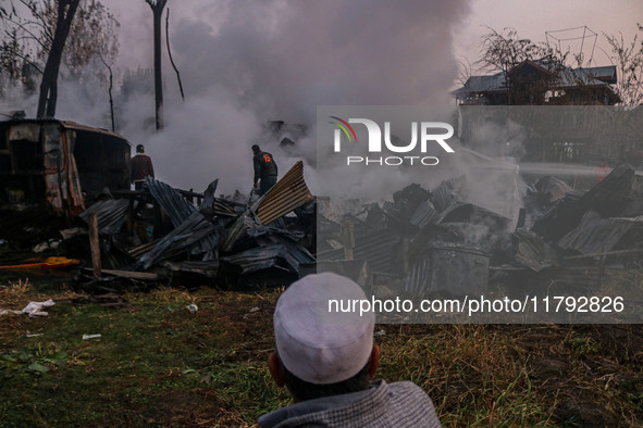 An elderly man watches as civilians work to extinguish a fire on residential houses in Srinagar, Jammu and Kashmir, on November 19, 2024. 