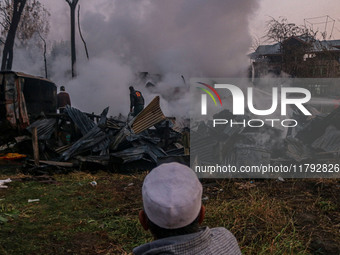 An elderly man watches as civilians work to extinguish a fire on residential houses in Srinagar, Jammu and Kashmir, on November 19, 2024. (