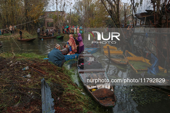 People transport their belongings in boats as firefighters and civilians work to extinguish a fire on residential houses in Srinagar, Jammu...