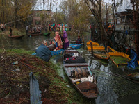 People transport their belongings in boats as firefighters and civilians work to extinguish a fire on residential houses in Srinagar, Jammu...