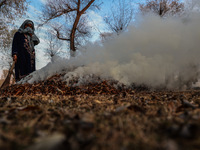 A couple burns dried leaves and twigs of trees to make charcoal on a cold autumn day in Sopore, Jammu and Kashmir, India, on November 19, 20...