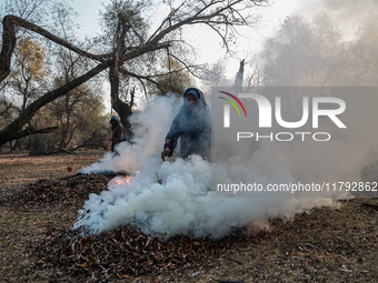 A couple burns dried leaves and twigs of trees to make charcoal on a cold autumn day in Sopore, Jammu and Kashmir, India, on November 19, 20...