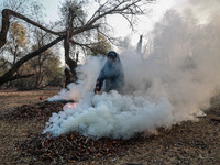 A couple burns dried leaves and twigs of trees to make charcoal on a cold autumn day in Sopore, Jammu and Kashmir, India, on November 19, 20...