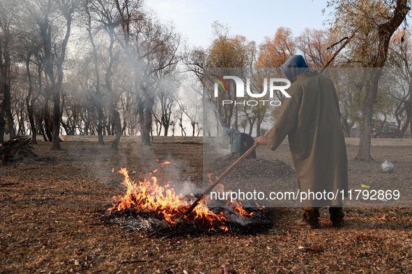 A couple burns dried leaves and twigs of trees to make charcoal on a cold autumn day in Sopore, Jammu and Kashmir, India, on November 19, 20...