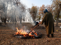 A couple burns dried leaves and twigs of trees to make charcoal on a cold autumn day in Sopore, Jammu and Kashmir, India, on November 19, 20...