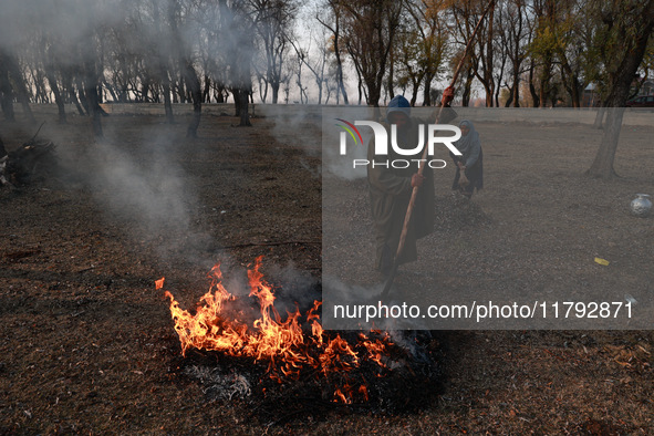 A couple burns dried leaves and twigs of trees to make charcoal on a cold autumn day in Sopore, Jammu and Kashmir, India, on November 19, 20...