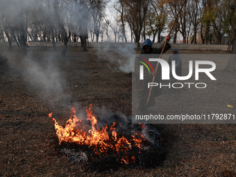 A couple burns dried leaves and twigs of trees to make charcoal on a cold autumn day in Sopore, Jammu and Kashmir, India, on November 19, 20...