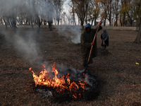 A couple burns dried leaves and twigs of trees to make charcoal on a cold autumn day in Sopore, Jammu and Kashmir, India, on November 19, 20...