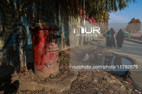 Girls walk past an old India Post letterbox in Sopore, Jammu and Kashmir, India, on November 19, 2024. 