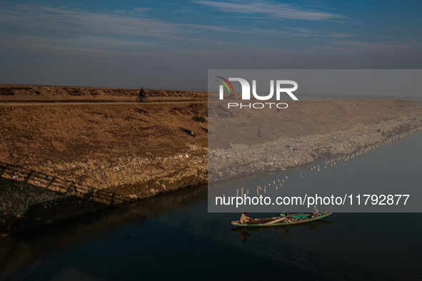 A boy rides a bicycle as fishermen row a boat in Wular Lake in Sopore, Jammu and Kashmir, India, on November 19, 2024. 