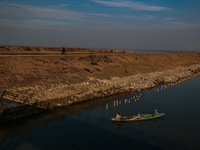 A boy rides a bicycle as fishermen row a boat in Wular Lake in Sopore, Jammu and Kashmir, India, on November 19, 2024. (