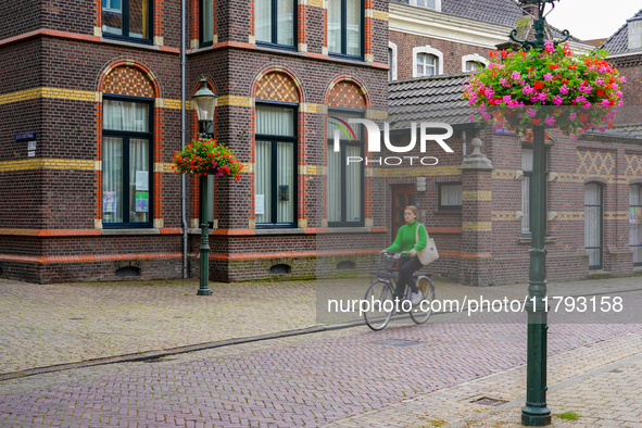 A woman cycles through the streets of Venlo, the Netherlands, on July 28, 2023. The street features cobblestones and is lined with detailed...