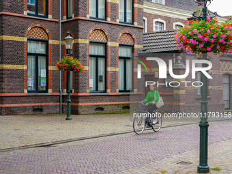 A woman cycles through the streets of Venlo, the Netherlands, on July 28, 2023. The street features cobblestones and is lined with detailed...