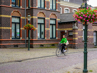 A woman cycles through the streets of Venlo, the Netherlands, on July 28, 2023. The street features cobblestones and is lined with detailed...