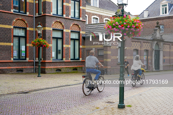 A couple rides their bicycles through the historic streets of Venlo, the Netherlands, on July 28, 2023. The cobblestone bicycle lane is surr...