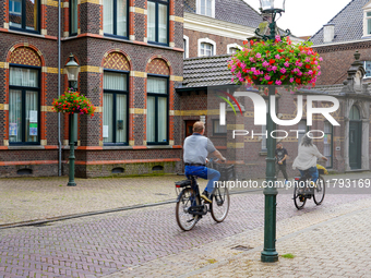 A couple rides their bicycles through the historic streets of Venlo, the Netherlands, on July 28, 2023. The cobblestone bicycle lane is surr...