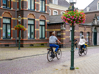 A couple rides their bicycles through the historic streets of Venlo, the Netherlands, on July 28, 2023. The cobblestone bicycle lane is surr...