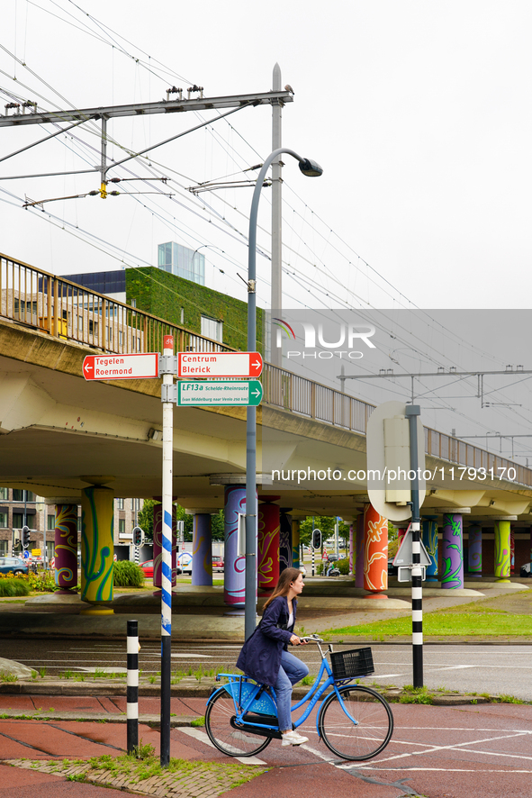 A young woman cycles through a designated bike path in Venlo, the Netherlands, on July 28, 2023. The scene is set against a backdrop of pain...