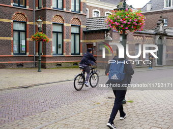 A cyclist and a pedestrian share the historic streets of Venlo, the Netherlands, on July 28, 2023. The scene is a mix of traditional Dutch a...