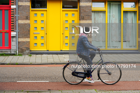 A man cycles past a striking apartment building in Venlo, the Netherlands, on July 28, 2023. The building's bold yellow doors and red detail...