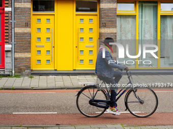 A man cycles past a striking apartment building in Venlo, the Netherlands, on July 28, 2023. The building's bold yellow doors and red detail...