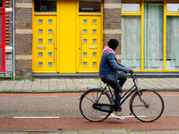 A man cycles past a striking apartment building in Venlo, the Netherlands, on July 28, 2023. The building's bold yellow doors and red detail...