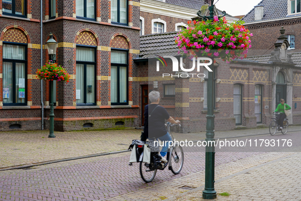 In Venlo, the Netherlands, on July 28, 2023, two women cycle through a scenic street. The cobblestone lane is lined with historic brick buil...