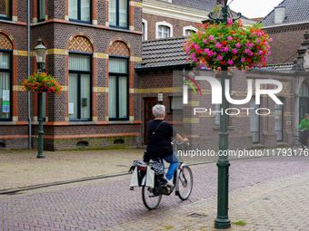 In Venlo, the Netherlands, on July 28, 2023, two women cycle through a scenic street. The cobblestone lane is lined with historic brick buil...