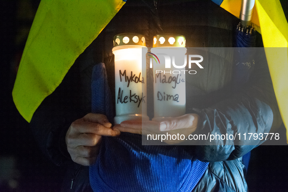 A protester holds a candlelight with victims' names as two hundred people take part in a demonstration to mark 1,000 days since the full-sca...