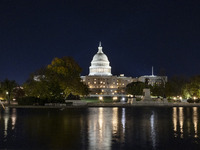 Night view with dark sky of the illuminated US Capitol reflecting on the pool water surface. The Capitol is the seat of the United States Co...